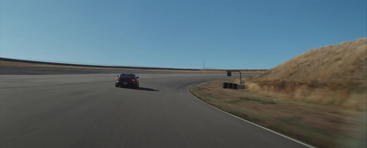 A sports car speeds along the freeway at midday cutting through a righthand turn