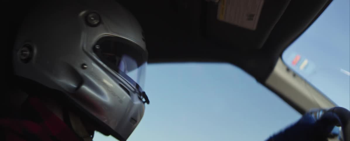 Race car driver wears a helmet as he turns the steering wheel