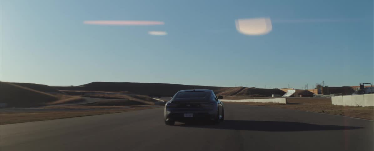 Sports car seen from behind driving along an asphalt track under a clear sky
