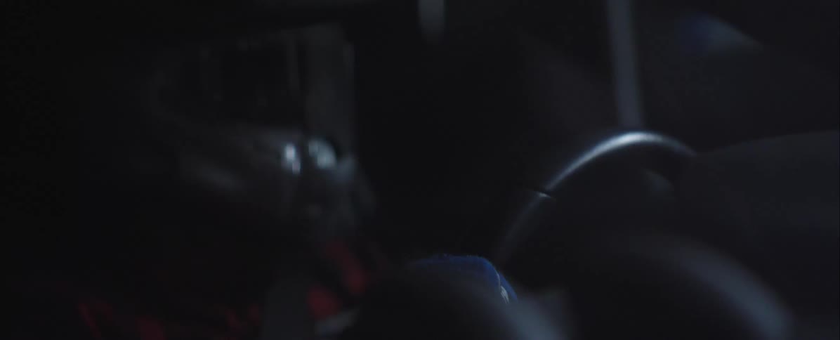A person drives at night wearing a helmet turning the cars steering wheel