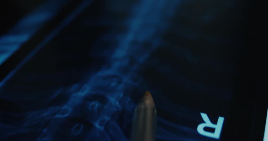 The pen is pointing at the xray of the spine that it lit up by the light