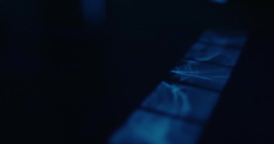 Blue light shines on a dark surface creating abstract square and rectangular reflections in a mysterious nighttime atmosphere