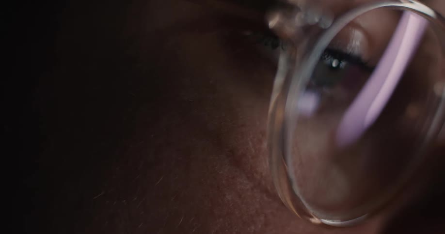 Glasses reflecting artificial light in a closeup of a face