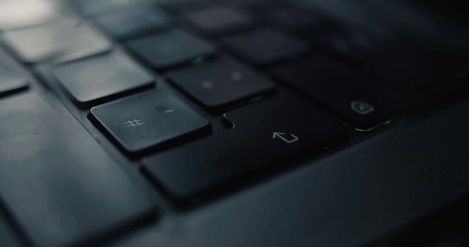 Finger pressing down arrow key on modern keyboard under dim ambient lighting