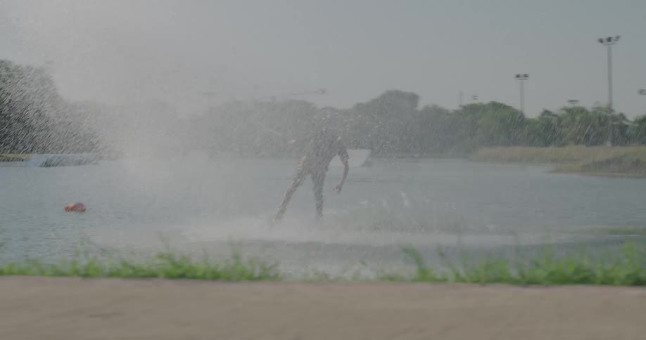 A man is wake boarding on a small lake on a sunny summer day