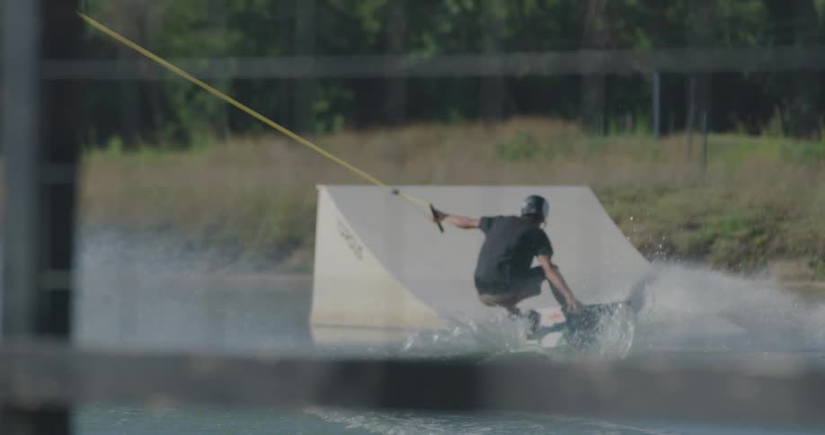 A man wakeboarding out to a jump