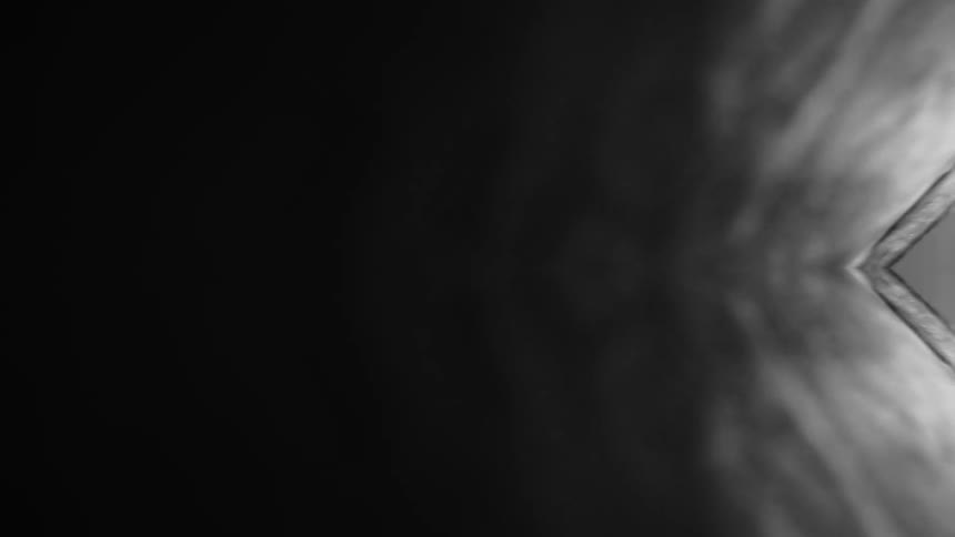 A dark abstract composition fades from deep black into soft gray tones forming a mirrored symmetrical pattern on the right that resembles rippling light or smoke converging toward a sharp luminous edge