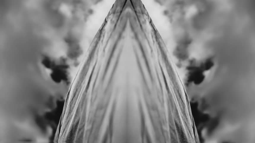 Grayscale triangular object with a patterned surface expands and shrinks against a cloudy background