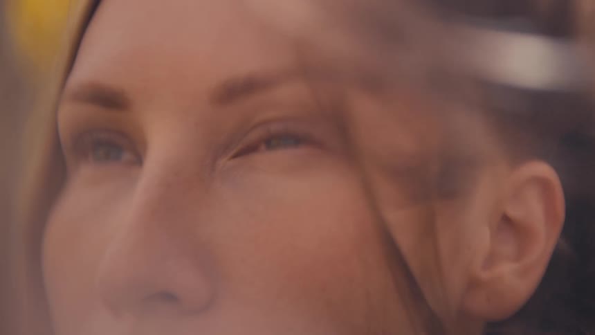 A very tight shallow depthoffield closeup on a womans face focusing on her eyes as she looks up with strands of hair moving in the gentle light