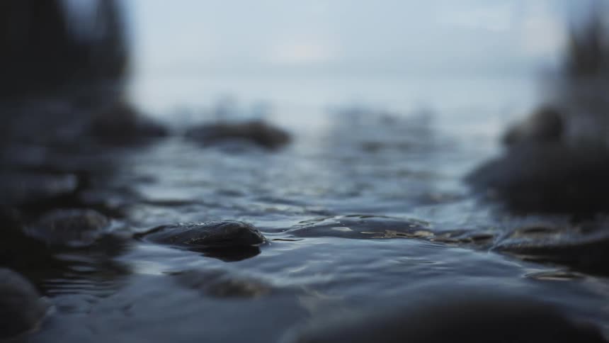Stones on the shoreline partially submerged in calm water