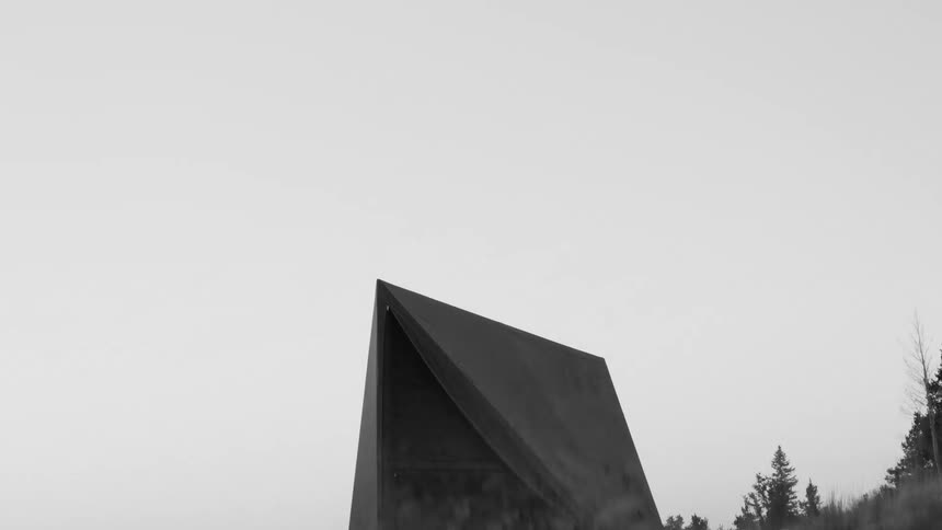 Dark tent set up in an open area with trees in the background