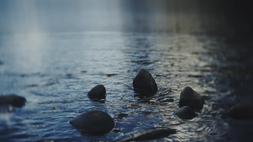 Stones emerging from shallow water with a rippled surface