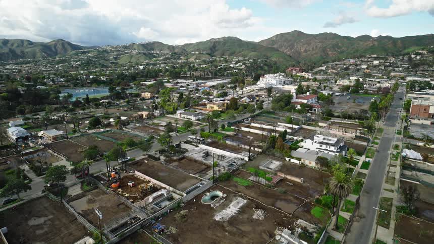 Aerial view of a neighborhood with multiple empty lots and hills in the background