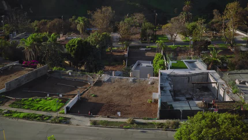 Partially demolished residential lots with exposed foundations and surrounding vegetation
