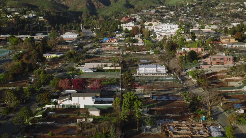 An aerial view captures a hillside residential neighborhood showing damaged properties