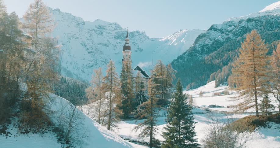 Alpine church surrounded by conifer trees in a snowy valley