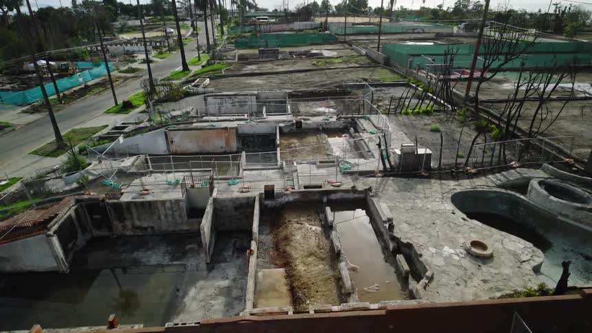 Abandoned concrete structure with flooded sections and residential streets surrounding it