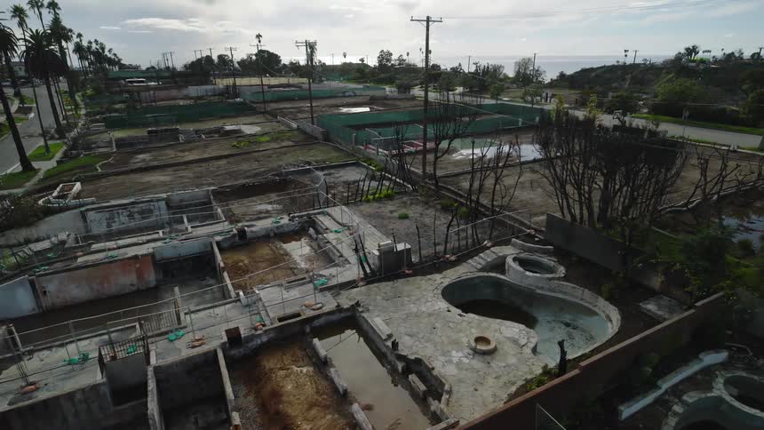 Aerial of a suburban area with abandoned sites and empty pools by the coast
