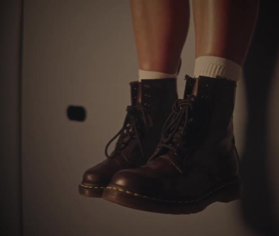 Black leather laceup boots seen on the feet of a seated person