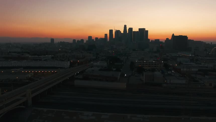 Urban skyline in silhouette at dawn with roads and warehouses in the foreground