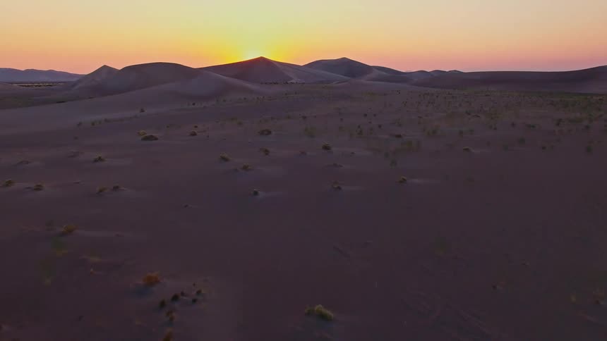 Aerial view of desert sand dunes with soft light over the landscape at sunset