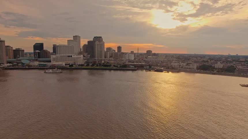 Aerial of a city skyline over a calm river with golden light at sunset