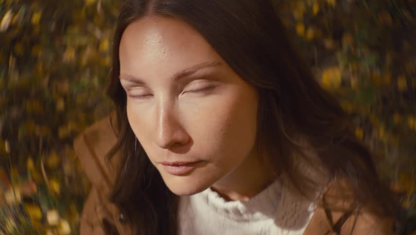 Closeup of a womans face with a blurred background of yellow leaves