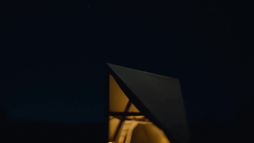 Illuminated structure with a triangular roof set against the night sky