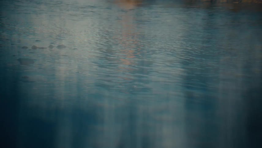 Calm water surface reflecting blue and golden tones