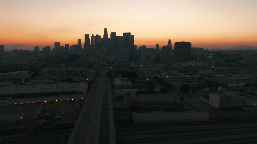 Urban skyline at dusk seen from above with a central avenue leading toward the buildings