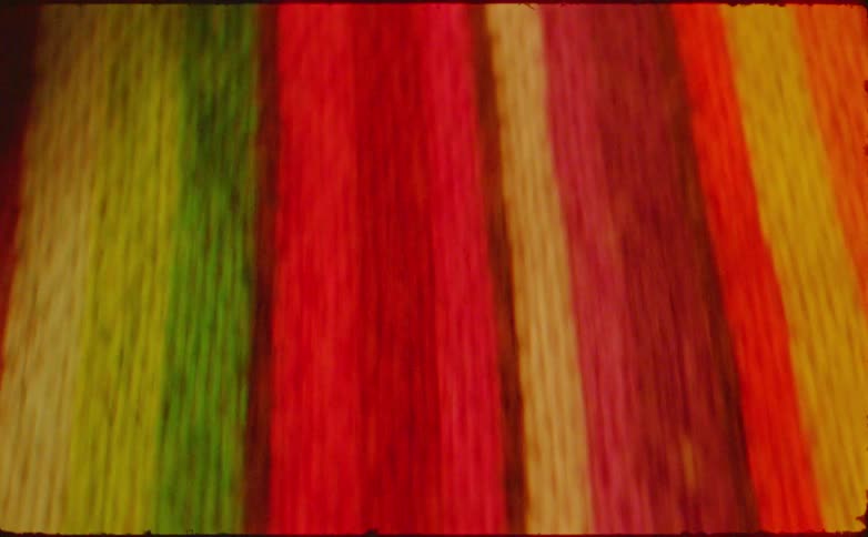 Blurry vertical streaks come into focus to reveal a close up of colorful striped fabric