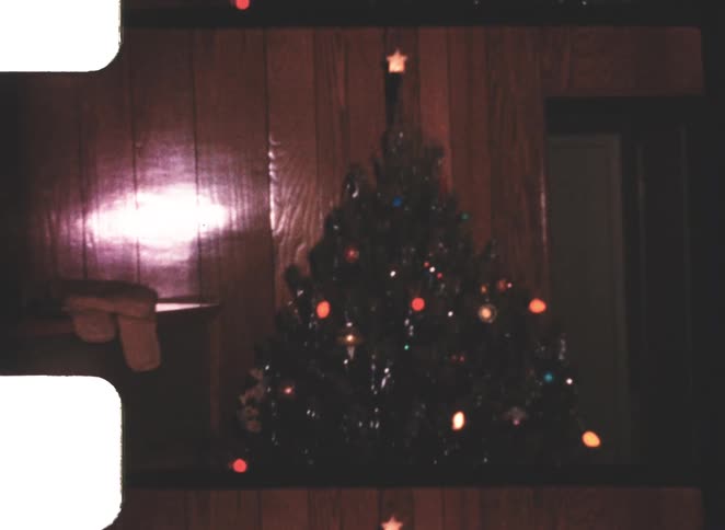 Lit christmas tree indoors with wood paneling