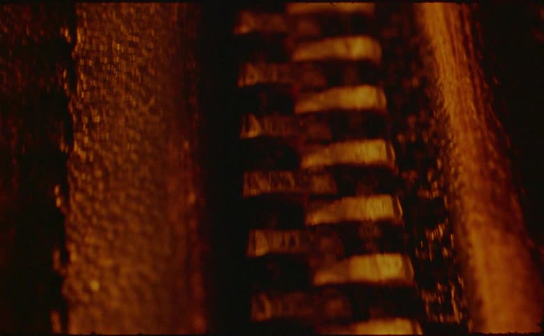 A close view of a dirty zipper with warm amber lighting and heavy cinematic grain creates a gritty texture