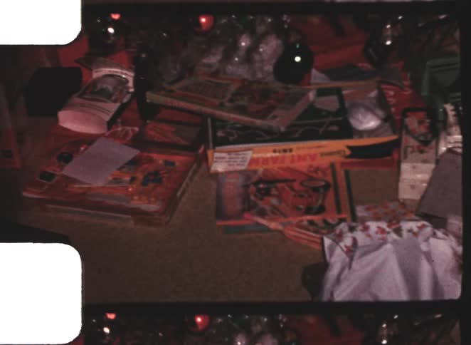 Several unwrapped presents are on the floor around a christmas tree