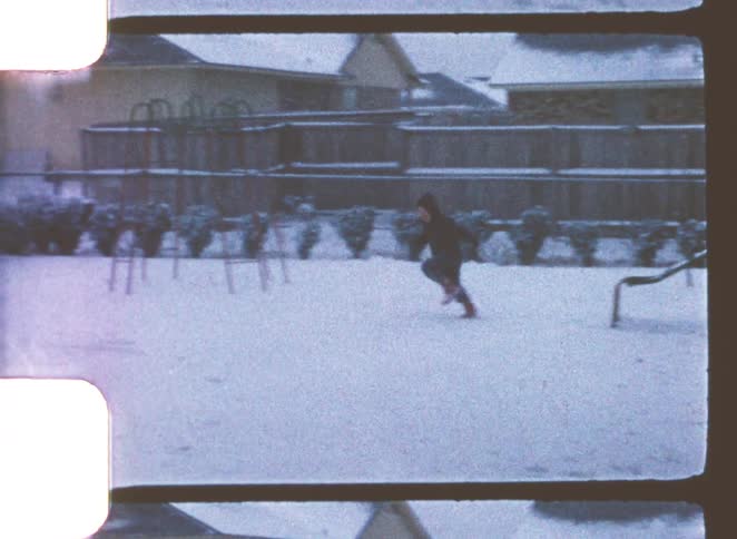 A young boy playing with his dog in a snowy backyard