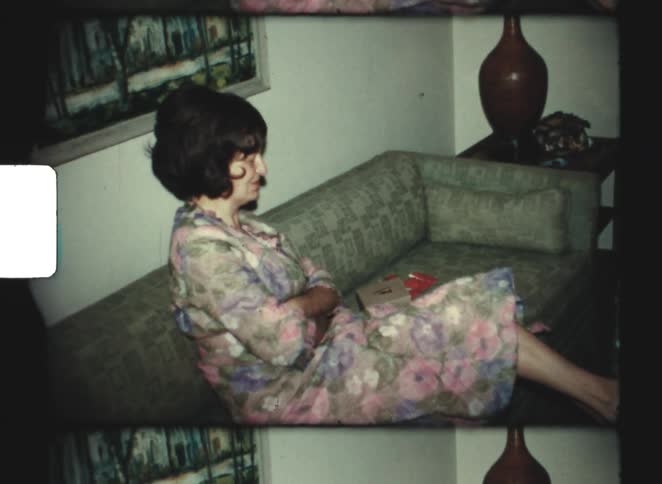 A young woman wearing a robe sitting on a couch in a living room