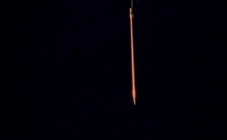 The video displays a single narrow object with a fiery glowing trail descending vertically against an otherwise completely black backgroundit creates a dramatic isolated visual effect suggesting a fastmoving projectile in the night sky