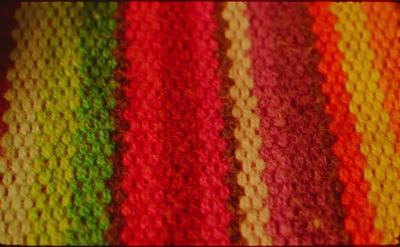 A closeup of colorful vertically striped fabric blurs into abstract streaks