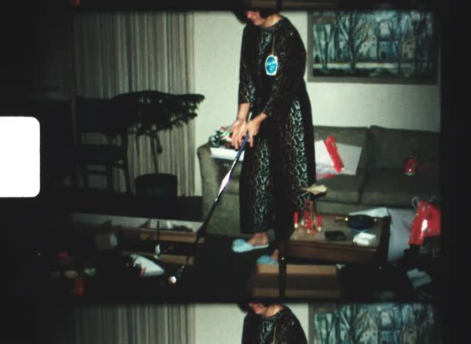 A woman playing with a golf stick while standing in a living room