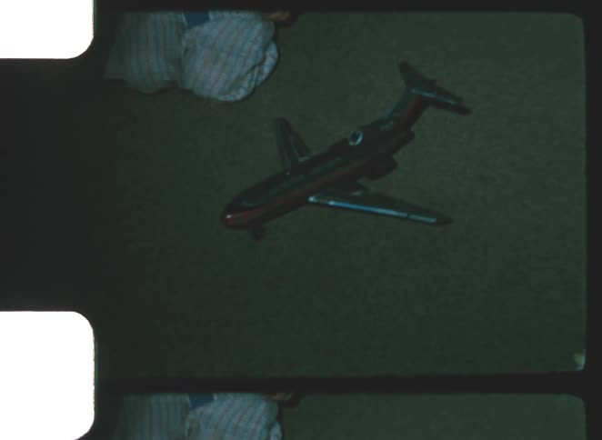 A kid wearing pajamas plays with a toy airplane in the living room at night the soft indoor lighting giving the scene a warm cozy feel