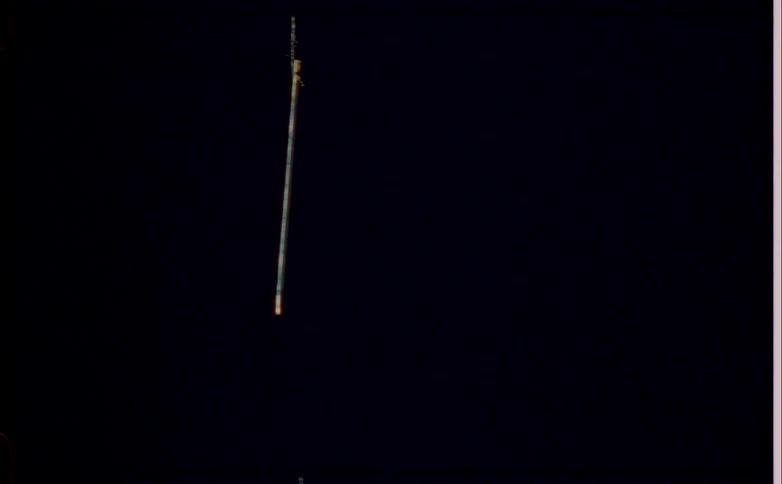 A long thin stick hangs vertically against a dark background
