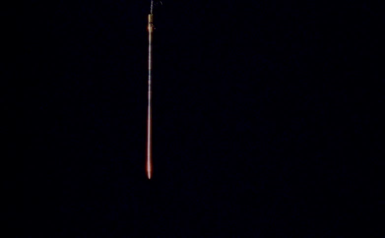 A close view of a stick dropping down and hanging in a dark atmosphere