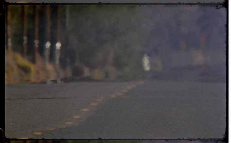 A freeway stretches through a rural area at midday lined on both sides with brown dry grasses