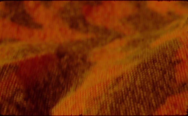 A yellow sweatshirt with a red art painting on the front lit clearly by bright sunlight