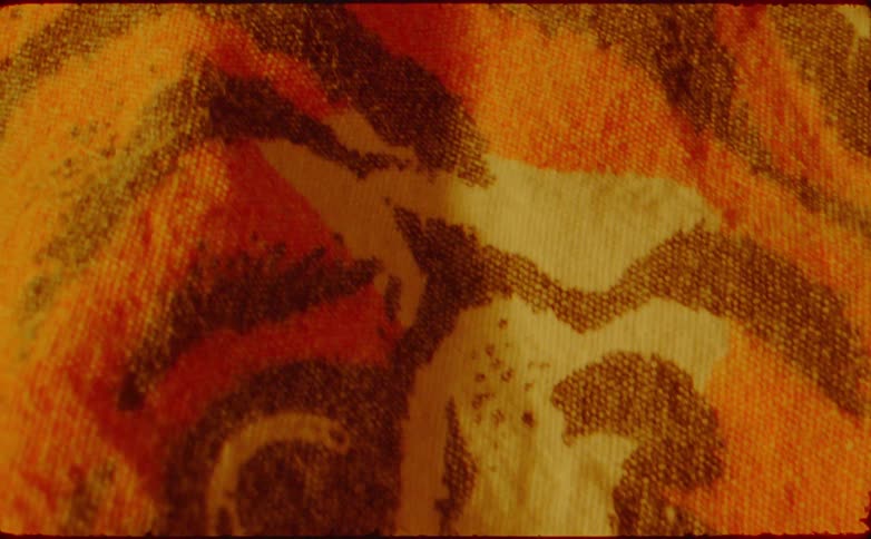 This video begins with a dark shot of a night sky then quickly transitions to a very closeup shaky sequence of abstract fabric patterns the patterns feature dominant colors of orange yellow and brown with some white elements suggesting a towel or