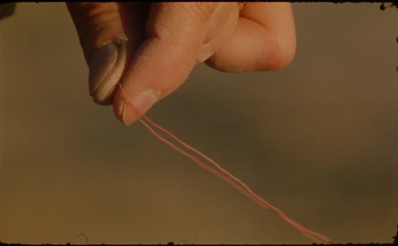 Close up of a person holding an orange thread piece