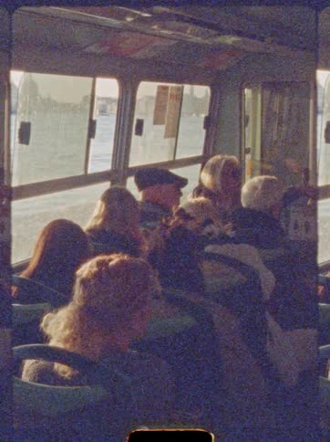 Passengers seated observe scenery through windows during daytime crossing on vessel