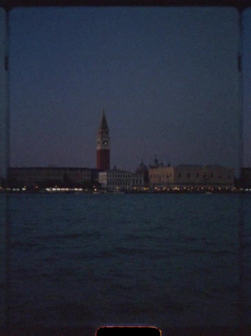 Nighttime sea view with a tower and illuminated buildings in the background