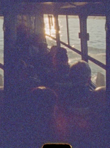 Passengers travel during late afternoon in vehicle with sunlit water view outside