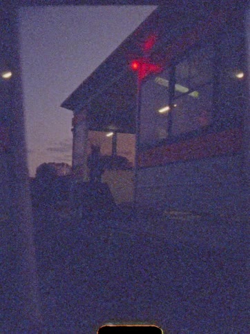 Building seen at dusk with red lights and illuminated interior
